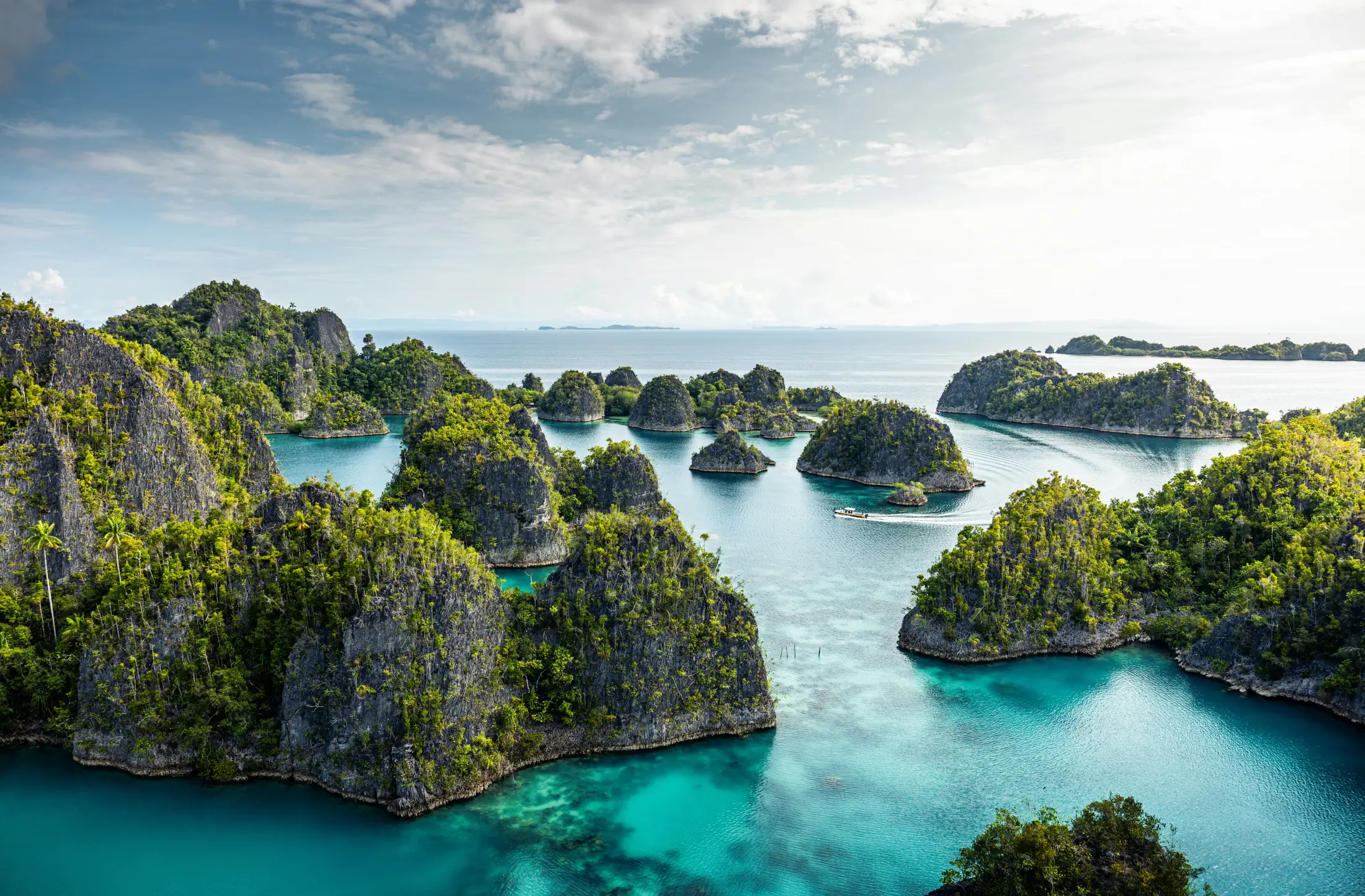 Wide view of forested limestone islands surrounded by turquoise water.
